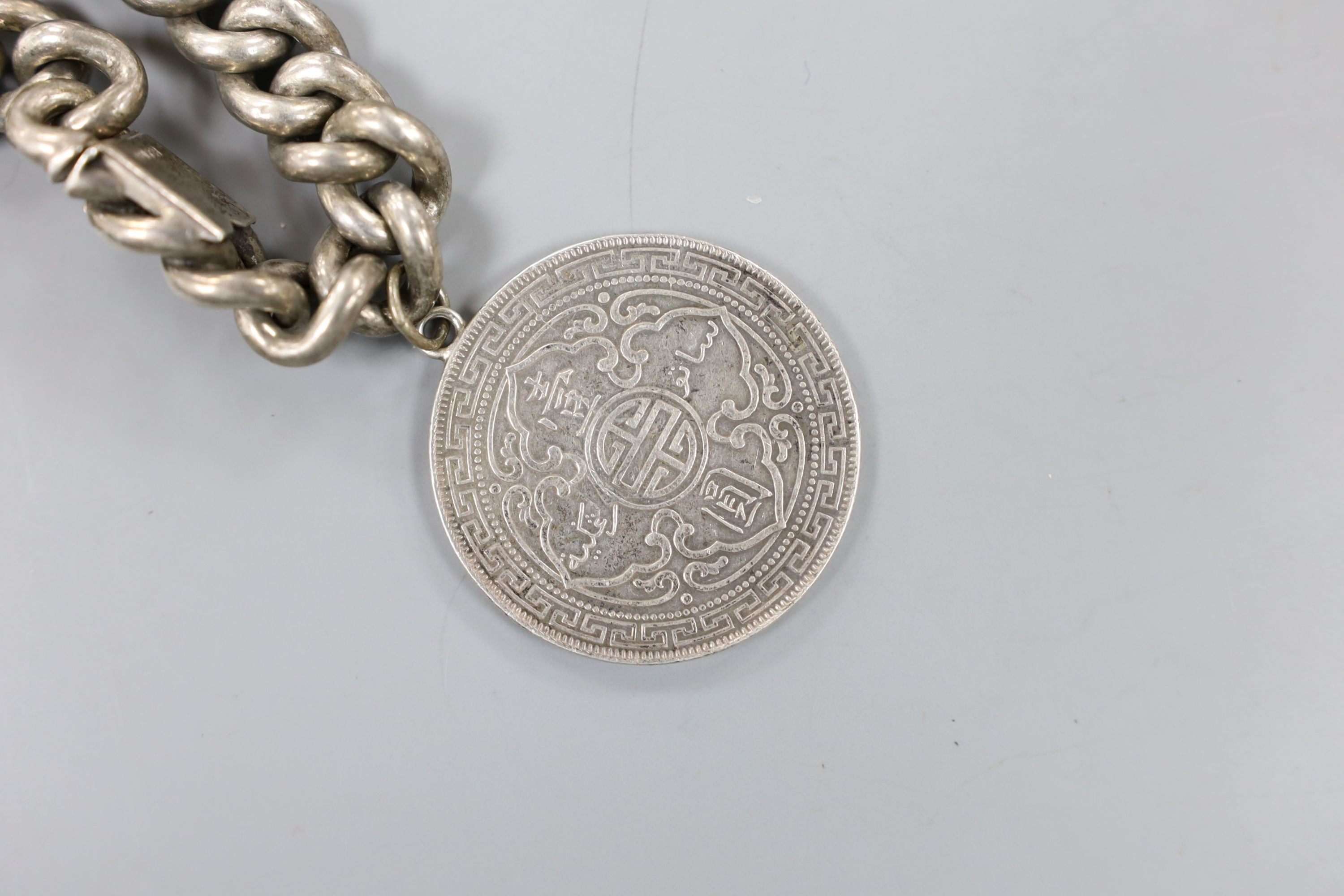 A German white metal and enamel bangle(a.f.) and an 835 white metal curb link bracelet hung with a one dollar coin.